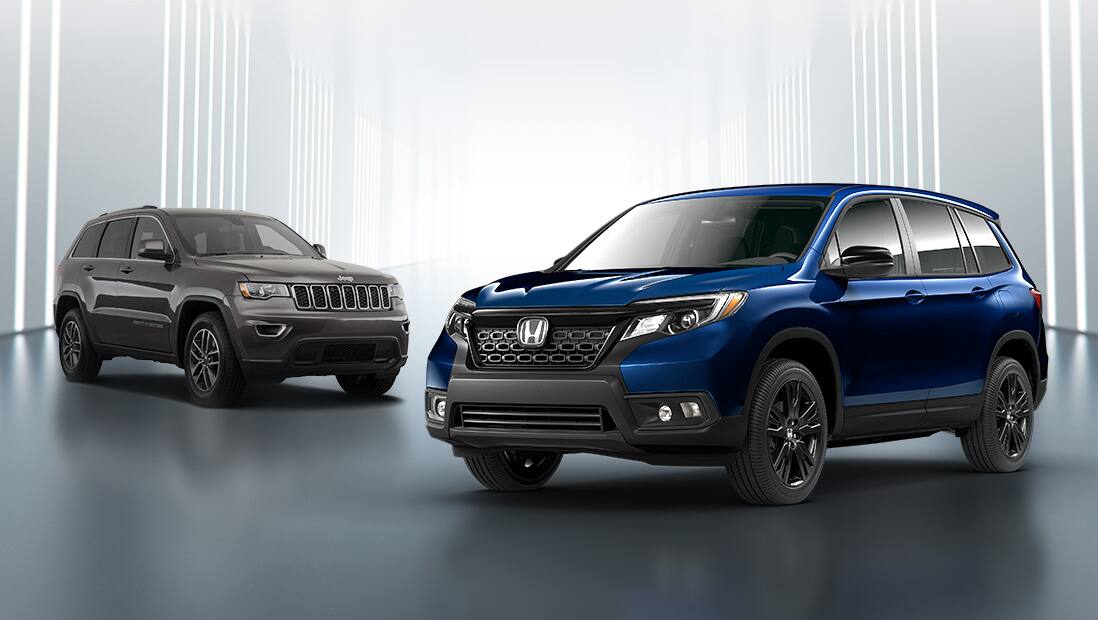 Front 3/4 driver’s side view of 2019 Honda Passport in Obsidian Blue Pearl parked in studio environment next to Jeep Grand Cherokee