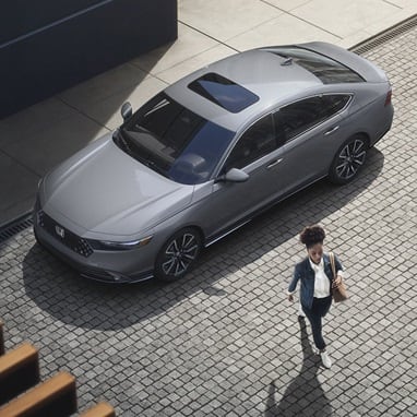 High angle of the 2026 Honda Accord parked in the city showing a person walking away from the vehicle.