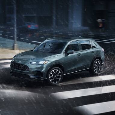 2027 Honda HR-V EX-L in Nordic Forest Pearl profile view driving on a rainy city street (Subcompact Crossover SUV).