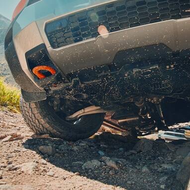 2027 Honda Passport TrailSport Elite in Sunset Orange front on a rugged rocky off-road mountain trail (Mid-Size SUV).